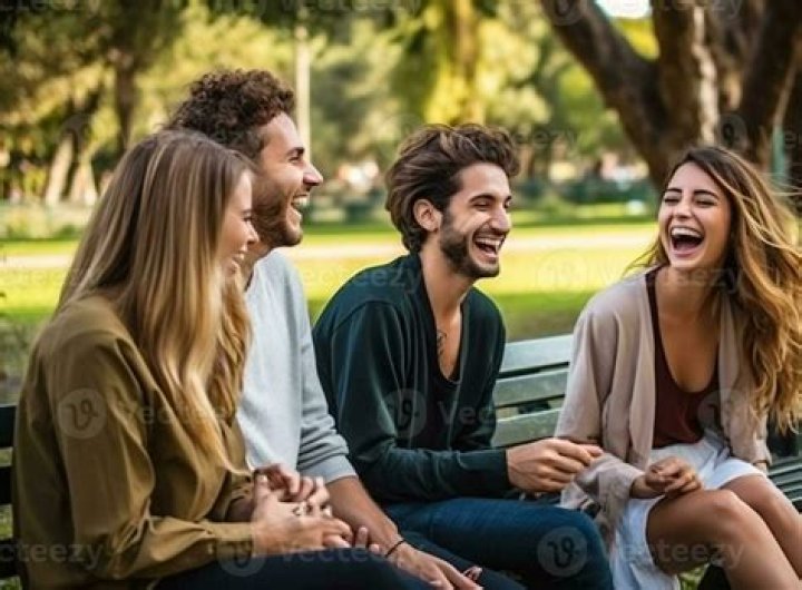A group of friends sitting around a campfire, laughing and talking.