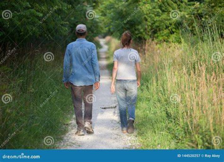 a man and woman walking down the street at night, one is wearing a scarf