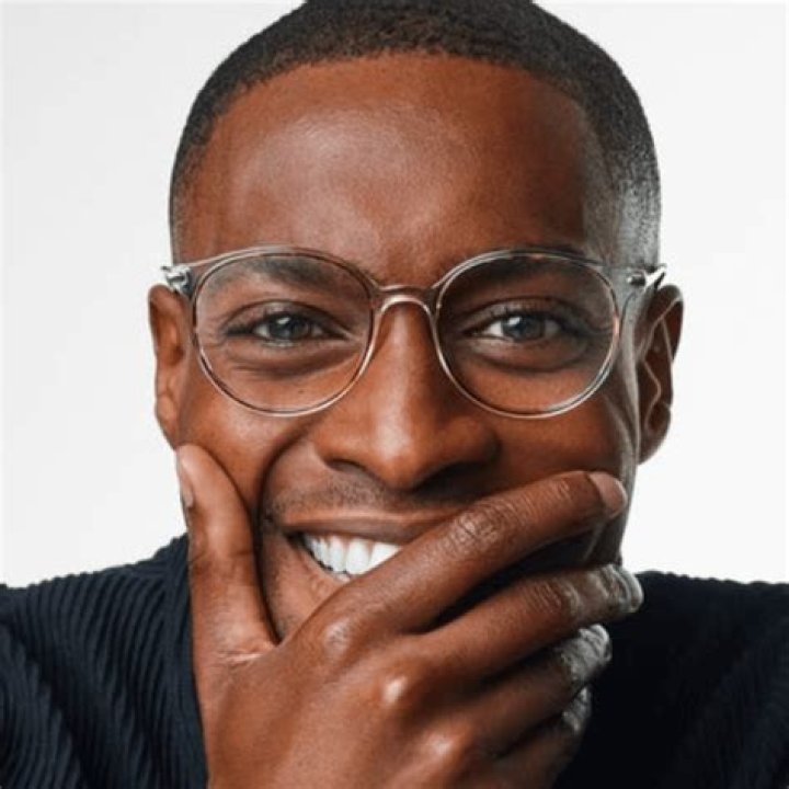 A man wearing glasses, a white shirt and a black jacket.