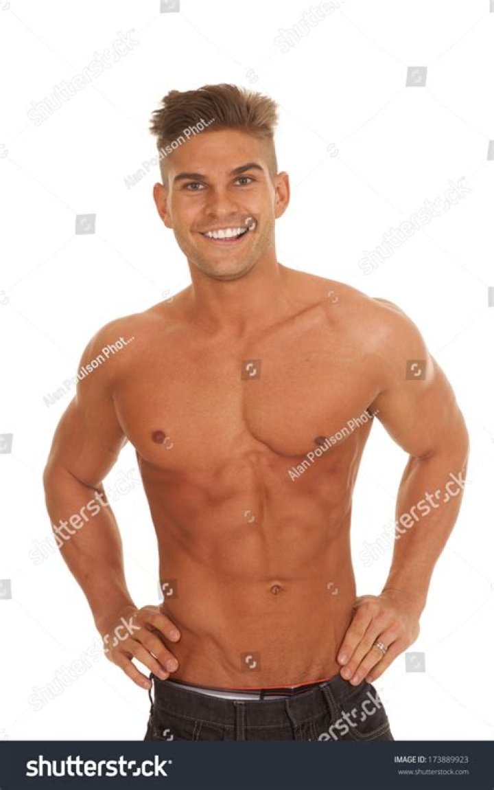 a man without a shirt is standing in the street with his shorts rolled