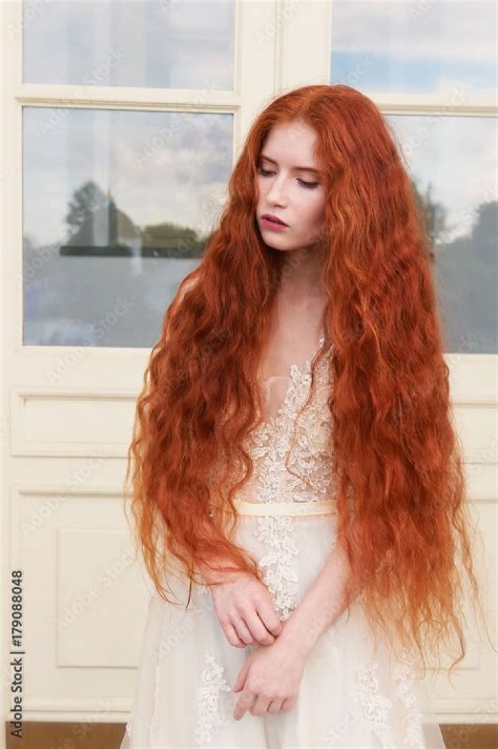 a woman with red hair wearing a white sweater and looking at the camera