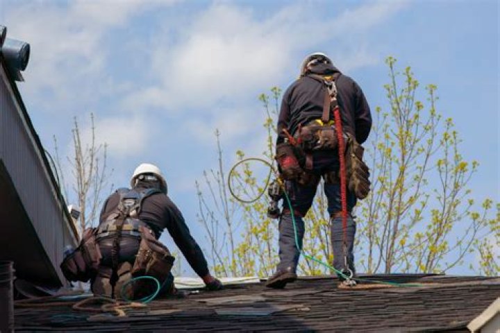 Man on roof performing emergency roof repair from damage from storm
