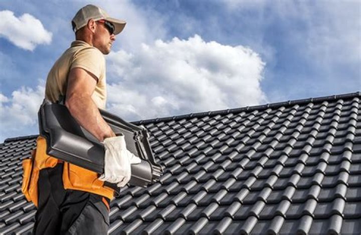 Man on roof with tools replacing the old roof with a new roof