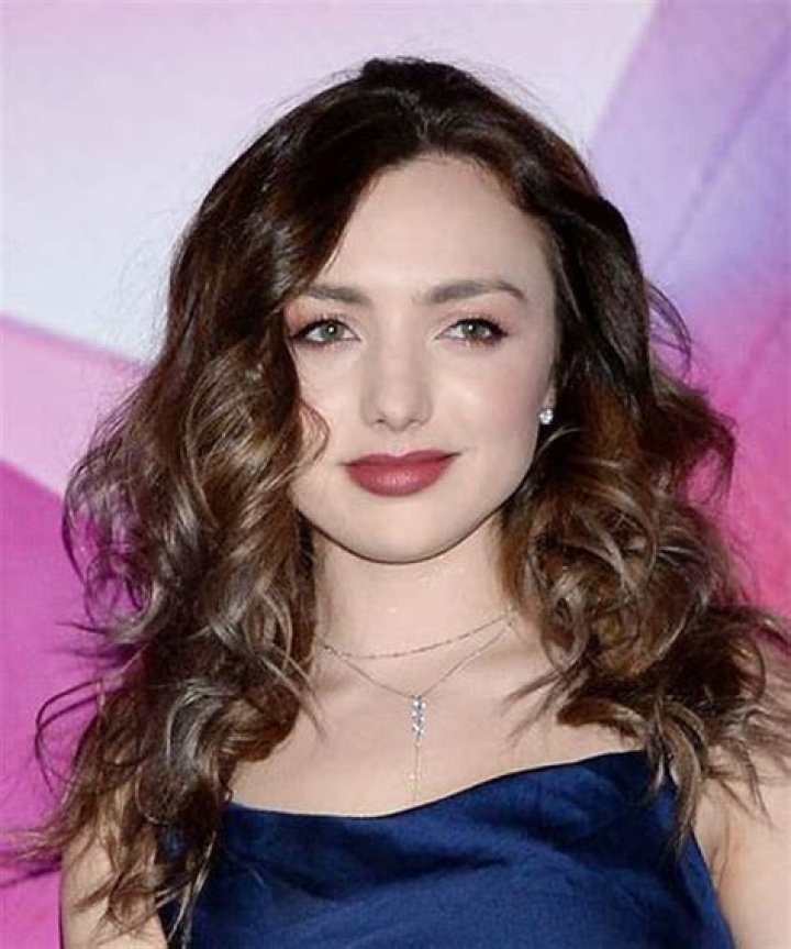 Peyton List Long Curly Dark Copper Hairstyle with Side Swept Bangs