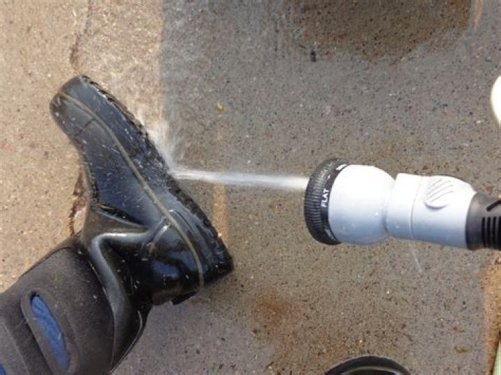 Spraying welly boots with disinfectant at fish farm