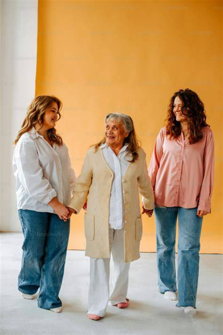 three women standing next to each other in front of a gray background